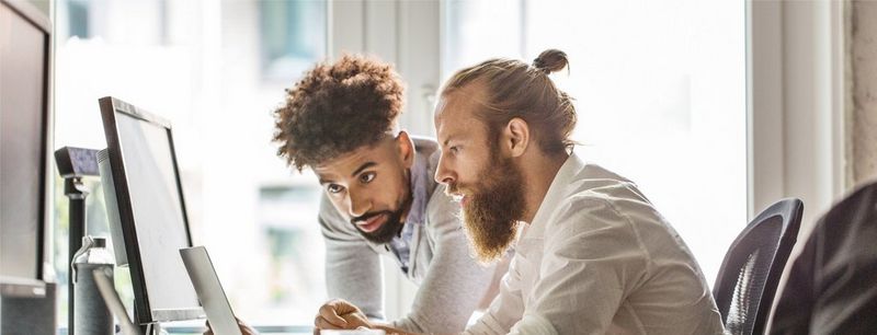 Two men in white look at computer screen